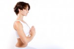 A woman in white adopting a pose of meditation.