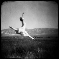 Dancer frolicking in the grass with a mountain in the background
