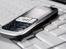 A cell phone laying on a keyboard