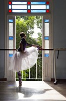 IMAGE Dancer Grettel Morejon of Ballet Nacional de Cuba stretches at the barre. Light streams through her skirt as she stands before a sunlit window. IMAGE