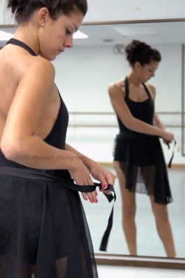IMAGE A dancer ties her black ballet skirt as she stands before the studio mirror. IMAGE