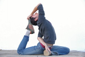 IMAGE An example of a Pigeon pose in Yoga by someone in jeans, a hoodie, and sneakers. IMAGE