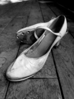 IMAGE Black and white photo of a well-worn pair of women's character tap shoes. IMAGE