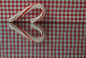 IMAGE A candy cane's tabletop reflection forms a heart. IMAGE