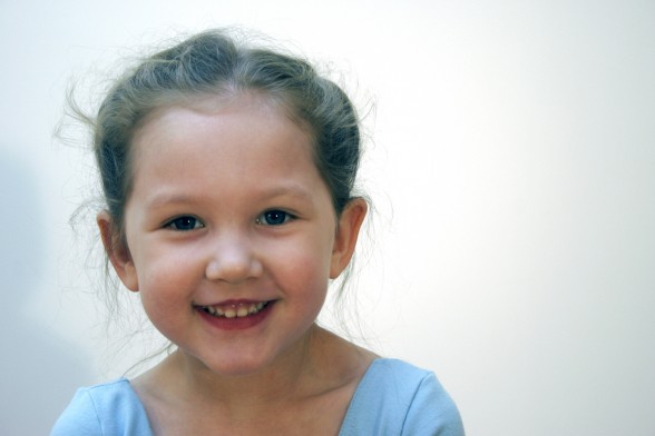 Tiny dancer in a light blue leotard with whispy hair and a big smile.