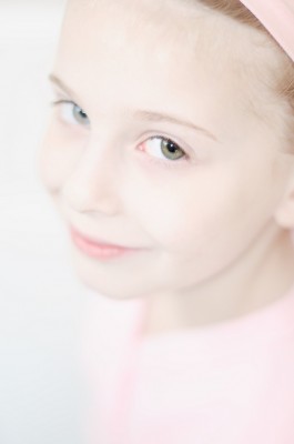 Portrait of a fair-haired young ballet dancer in pink leoard and headband