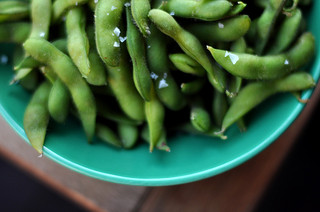 Edamame sprinked with salt and sitting in a green bowl.