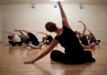 Class of dancers sitting, stretching side. Photo by Savage Rose Photography
