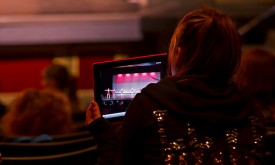 A dance mom captures her performing child on an ipad