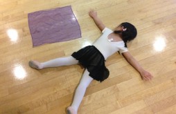 A young dancer flat on the floor like her scarf.