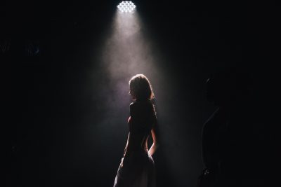 a woman stands in a spotlight
