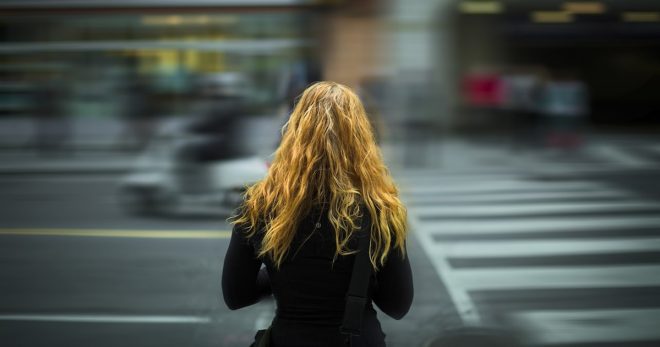 A woman stands at a city street crossing