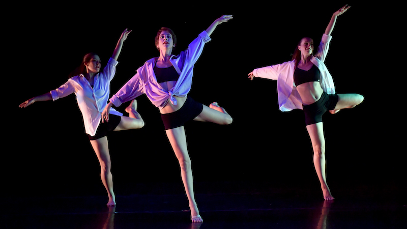 Three dancers in loose tops over black basics.